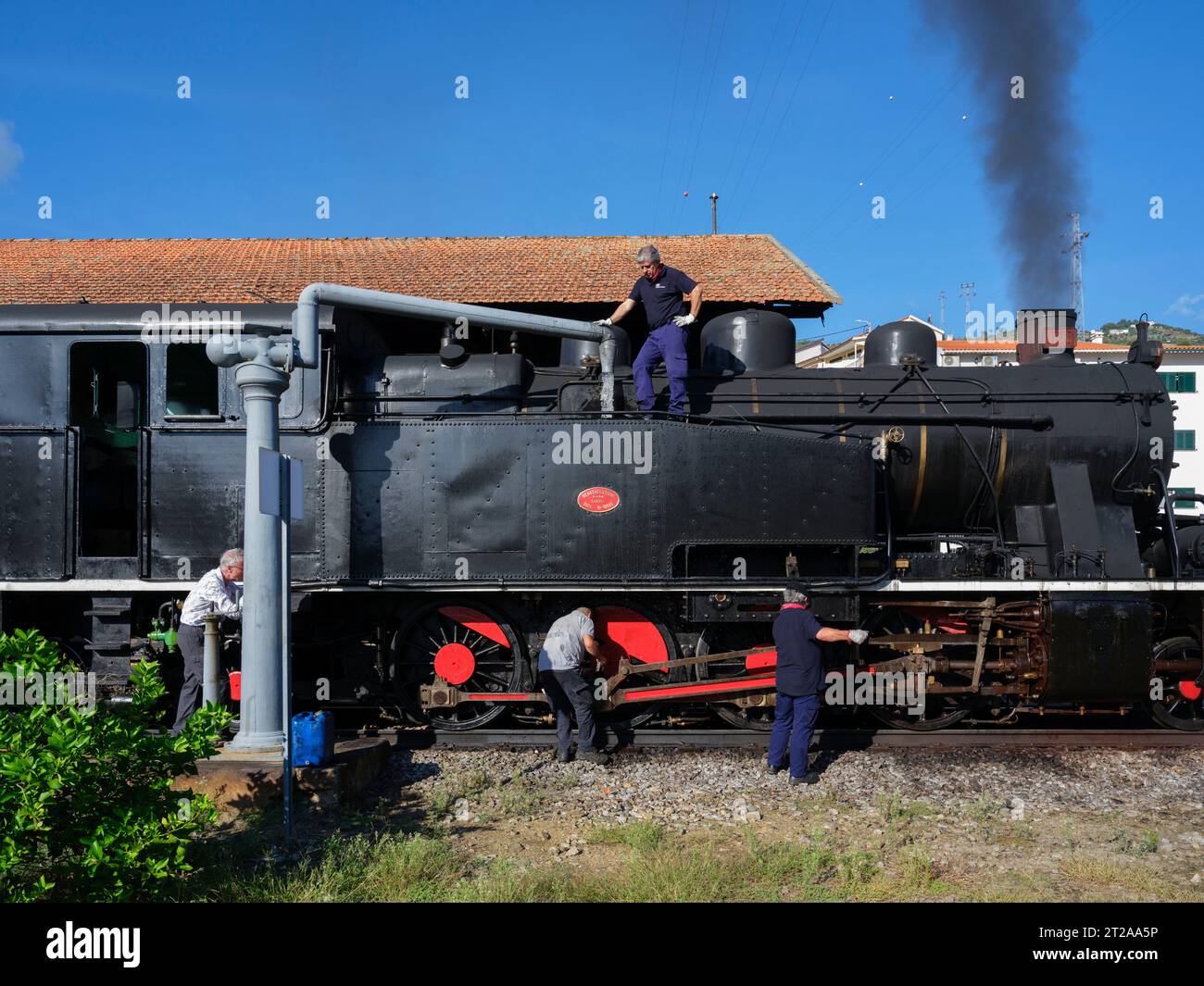 Lavoratori che caricano la locomotiva a vapore d'epoca del treno storico Douro con wa. Corre tra Régua e tua seguendo il fiume Douro, in Portogallo Foto Stock