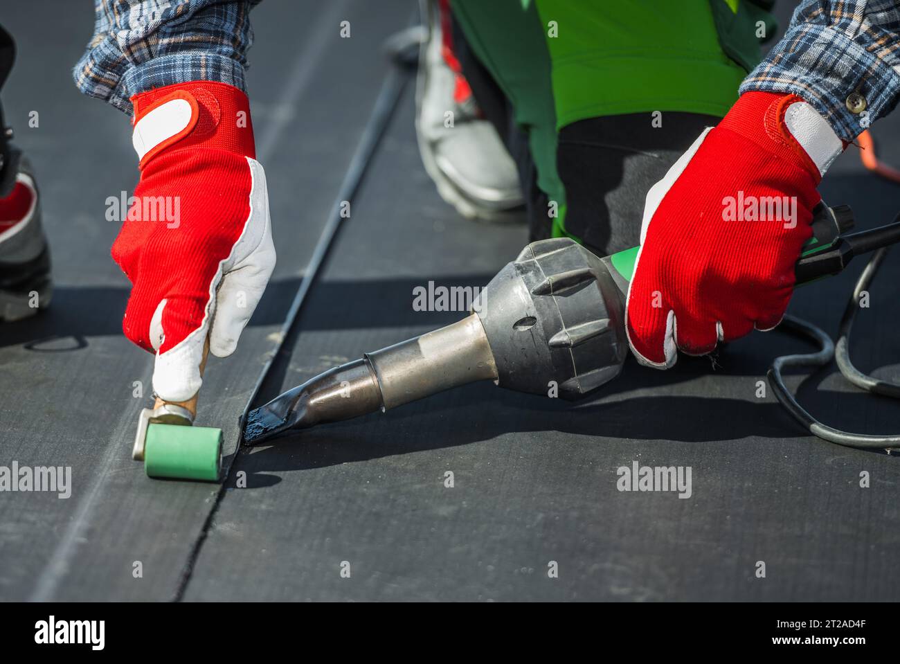 Foto ravvicinata di un appaltatore che copre il tetto dell'edificio con materiale in gomma vinilica EPDM. Foto Stock