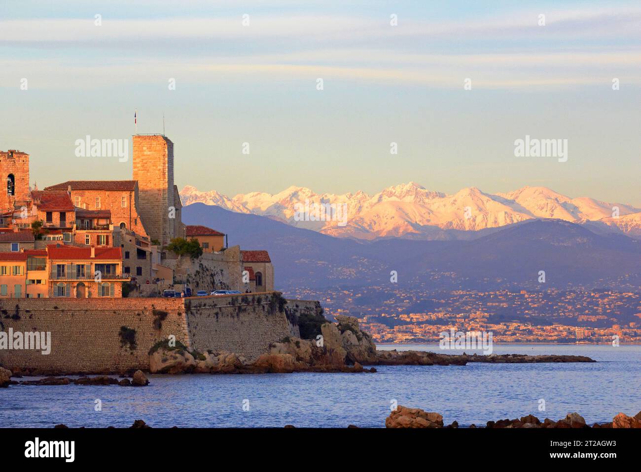 Storica città costiera di Antibes con vista sulle montagne al tramonto nel sud della Francia che mostra le pareti del mare e i bastioni con le montagne innevate Foto Stock