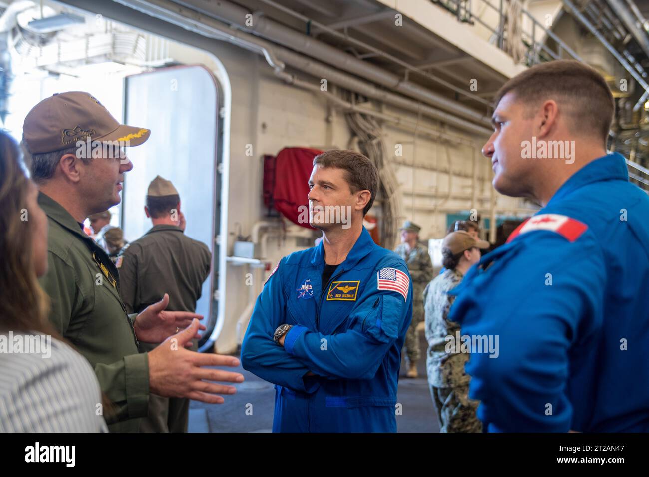 L'equipaggio di Artemis II visita la base navale di San Diego. Nave attraccata per il trasporto anfibio USS John P. Murtha (LPD 26) Comandante ufficiale capitano Doug Langenberg, a sinistra, spiega all'astronauta NASA al capitano Reid Wiseman della Marina degli Stati Uniti e all'astronauta dell'Agenzia spaziale canadese Jeremy Hansen, a destra, capacità di recupero della nave, 19 luglio 2023. In preparazione alla missione con equipaggio della NASA Artemis II, che manderà quattro astronauti in Orion oltre la Luna, la NASA e la Marina degli Stati Uniti condurranno una serie di test per dimostrare e valutare i processi, le procedure e l'hardware utilizzati nelle operazioni di recupero per la missione lunare con equipaggio Foto Stock