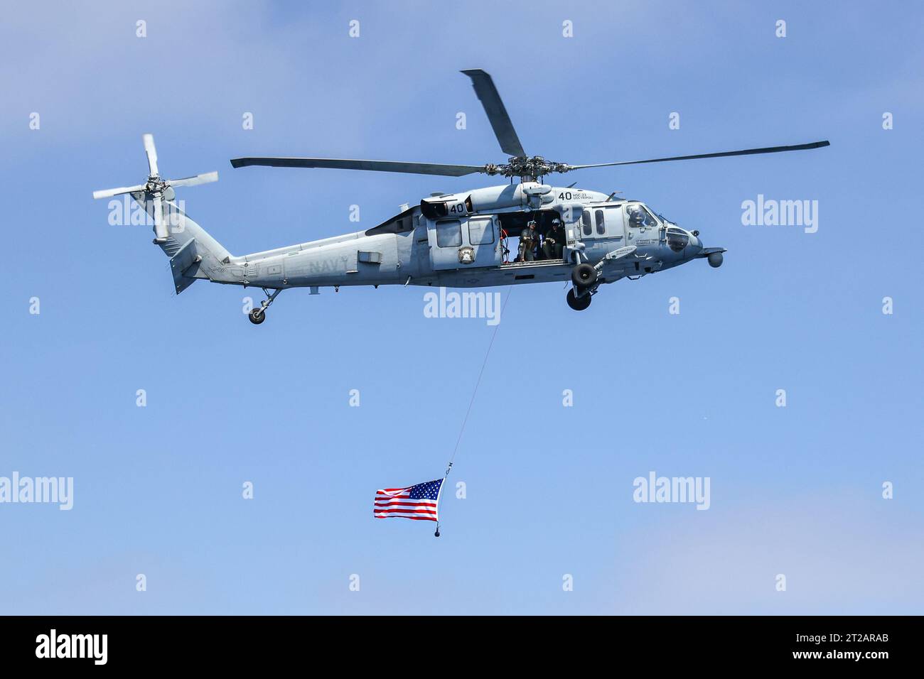 Artemis II Orion in corso Recovery test 10 (URT-10) - Day 4. I piloti di elicotteri navali dell'Helicopter Sea Combat Squadron (HSC) 23 "wildcard" sorvolano la USS John P Murtha con una bandiera americana dopo aver completato le operazioni di volo durante una simulazione di missione Artemis II durante il test di recupero 10 della NASA al largo della costa di San Diego. Foto Stock