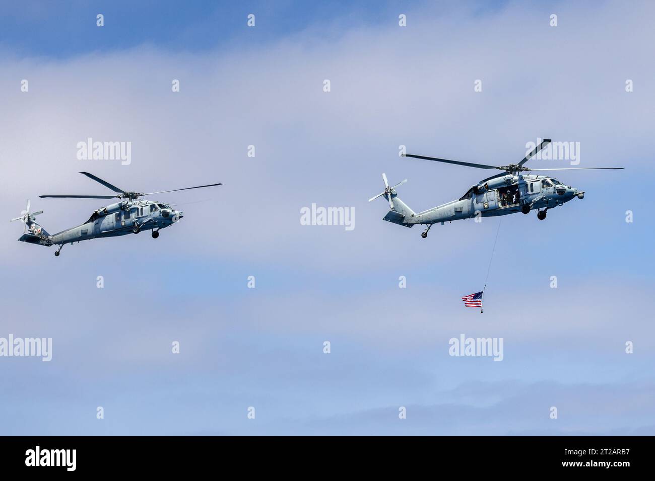 Artemis II Orion in corso Recovery test 10 (URT-10) - Day 4. I piloti di elicotteri navali dell'Helicopter Sea Combat Squadron (HSC) 23 "wildcard" sorvolano la USS John P Murtha con una bandiera americana dopo aver completato le operazioni di volo durante una simulazione di missione Artemis II durante il test di recupero 10 della NASA al largo della costa di San Diego. Foto Stock