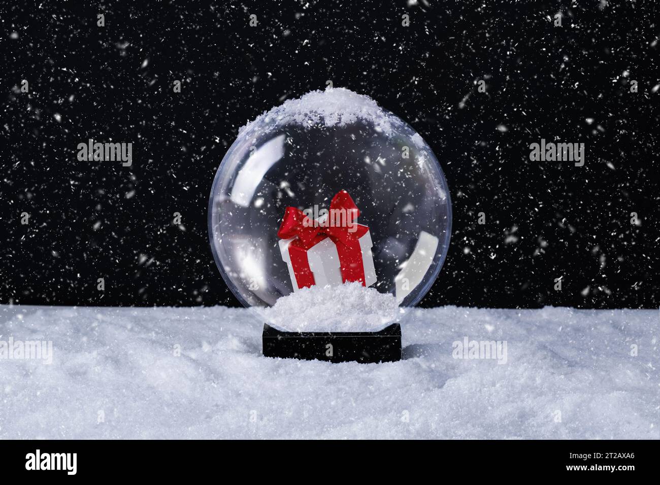 Magico globo di neve natalizio con un regalo di Natale all'interno su sfondo innevato. Biglietto d'auguri per Natale o Capodanno. Foto Stock