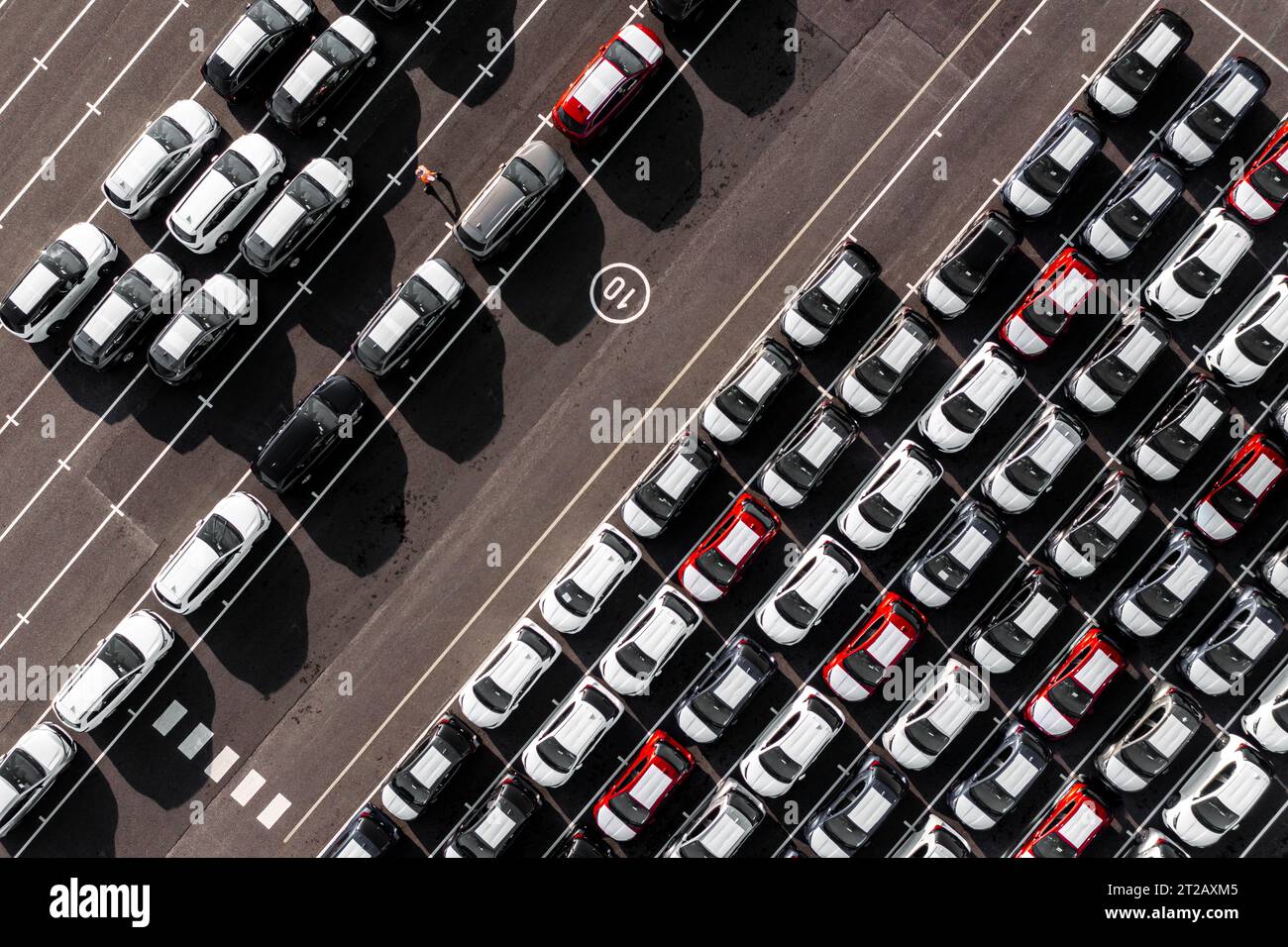 Vista aerea direttamente sopra file di auto di nuova costruzione nel settore automobilistico su un molo commerciale pronto per essere caricato per le tariffe di esportazione e importazione Foto Stock
