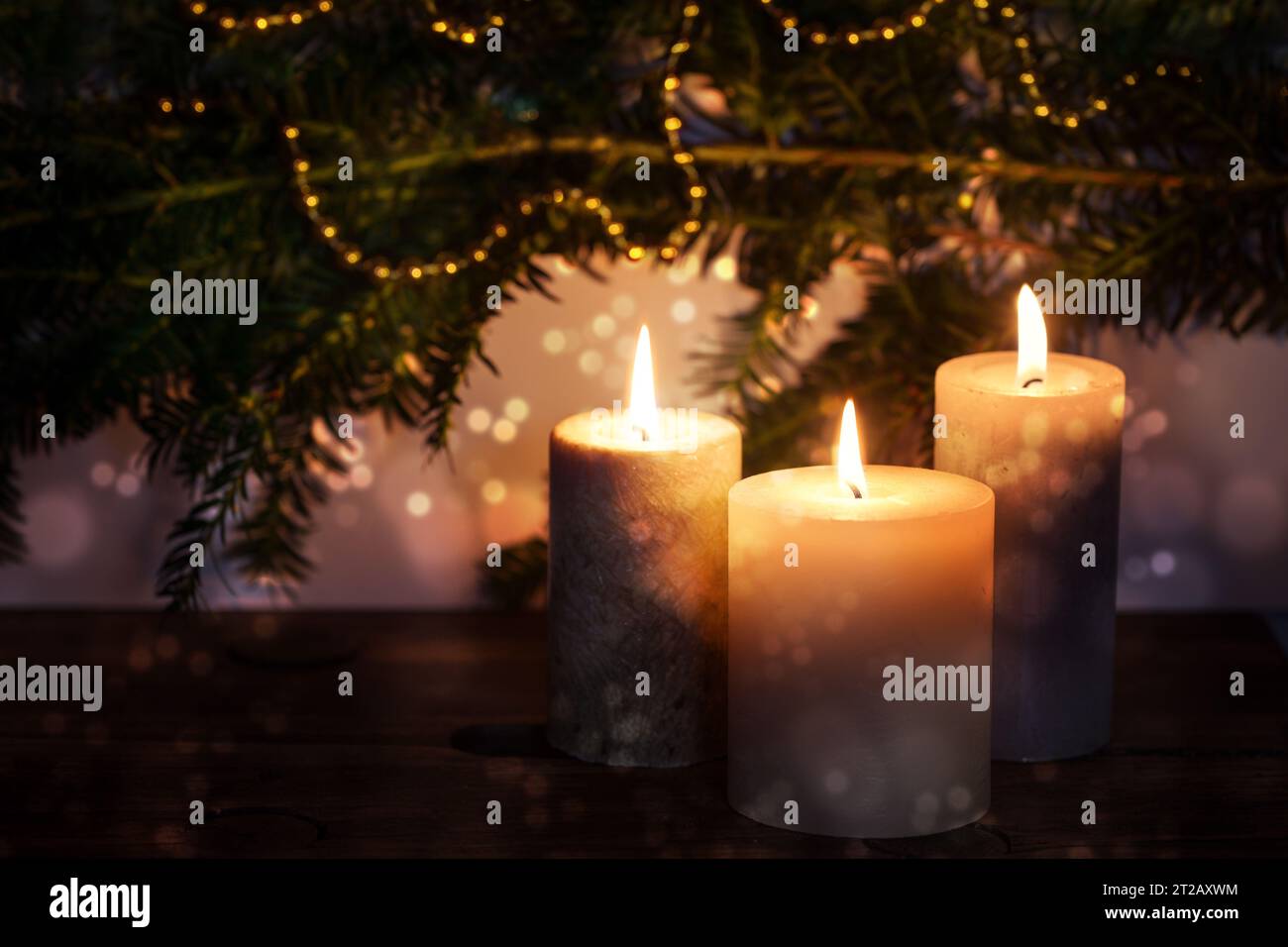 Tre candele in fiamme davanti ai rami di abete scuro con decorazioni natalizie e bolle di bokeh, biglietto d'auguri per le festività stagionali, spazio per le copie, selezione Foto Stock