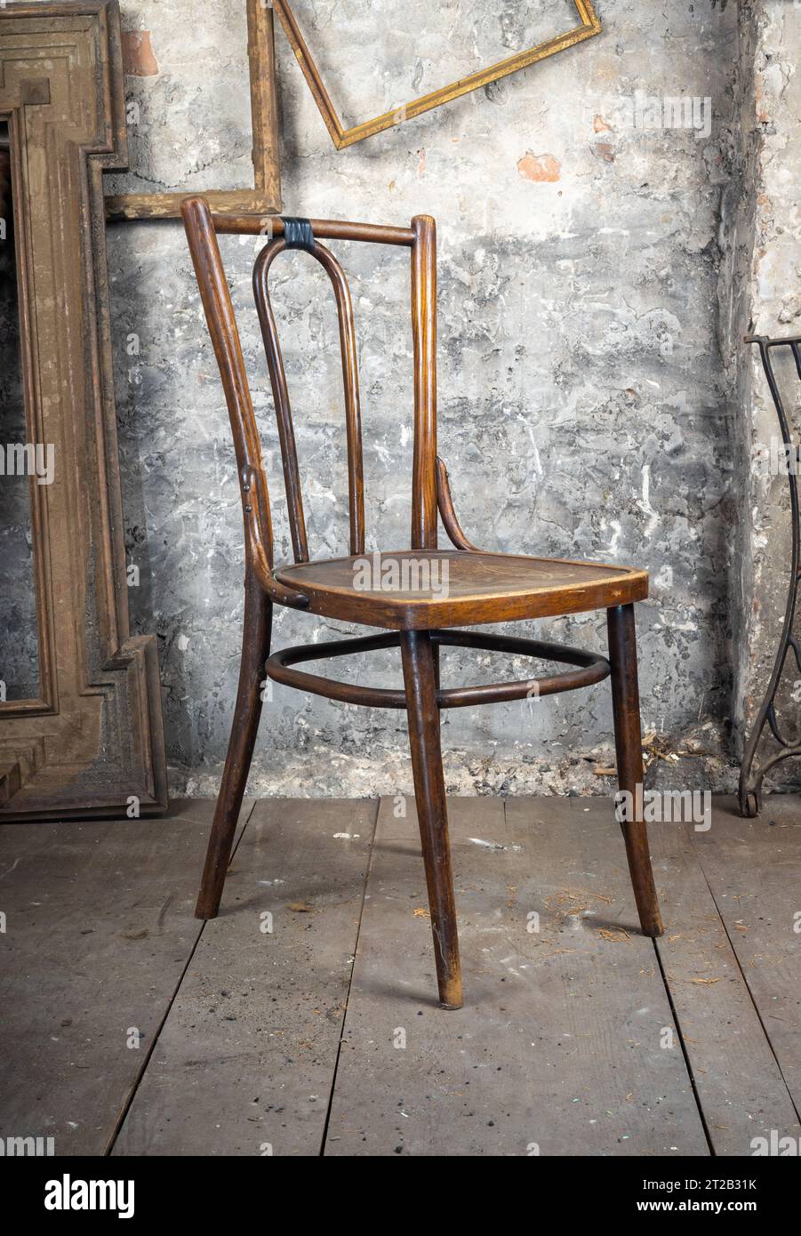 Stile vintage. La vecchia sedia rotta difettosa in una vecchia camera sporca con altre cose d'epoca Foto Stock