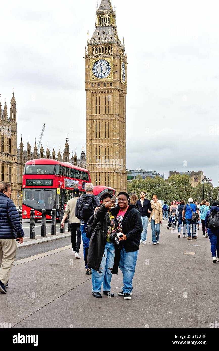 Due afroamericane che scattano un selfie sul Westminster Bridge con un autobus rosso di Londra e il Big Ben dietro di loro, Central London England Foto Stock