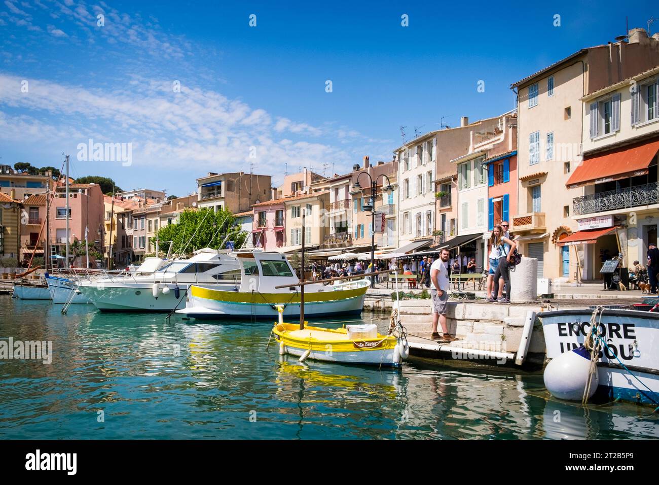 Persone in piedi o a piedi lungo il porticciolo sul lungomare al porto di Cassis, nel sud della Francia. Foto Stock