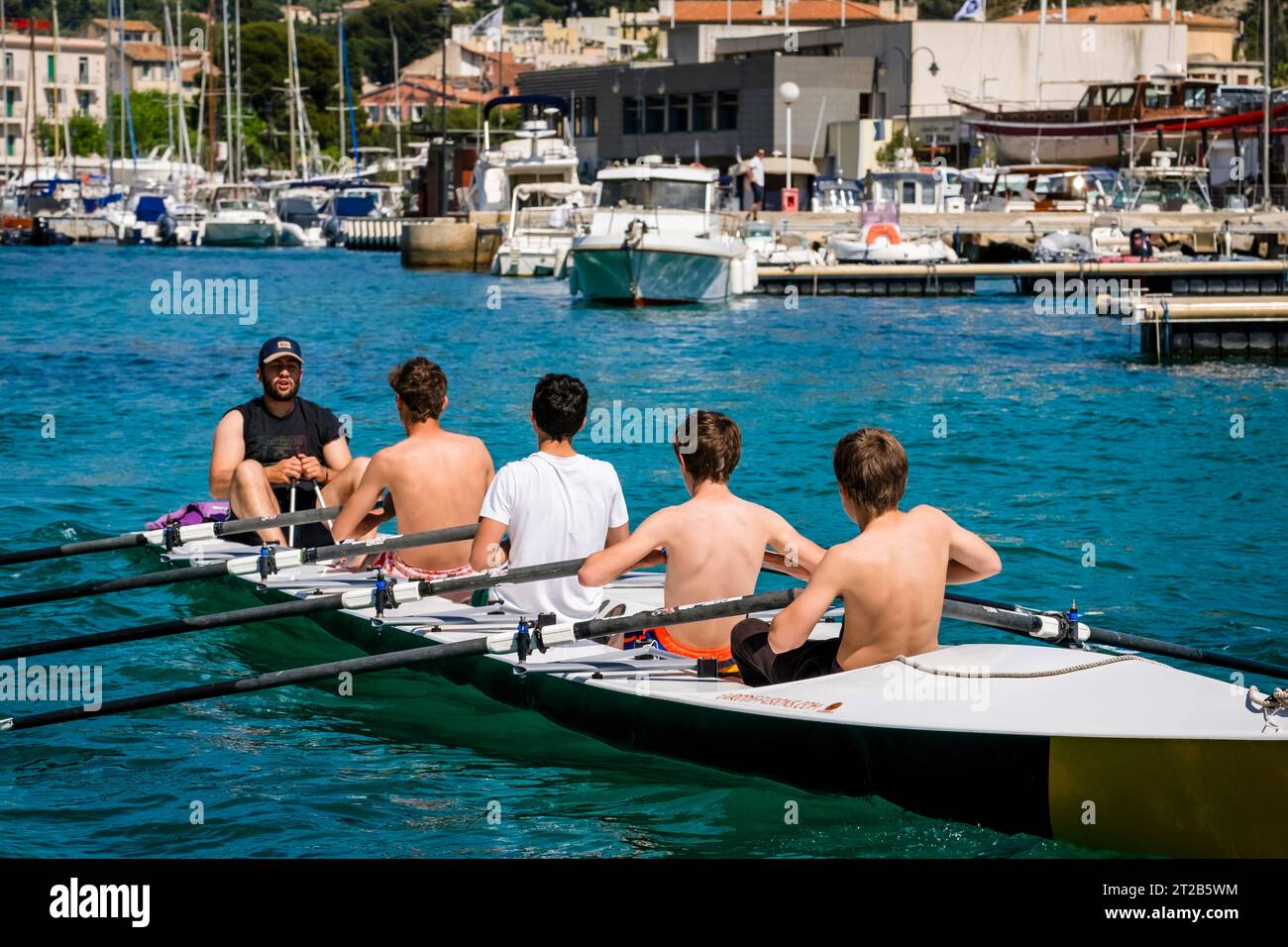 Un istruttore insegna a quattro ragazzi adolescenti a remare nel porto di Cassis, nel sud della Francia. Foto Stock