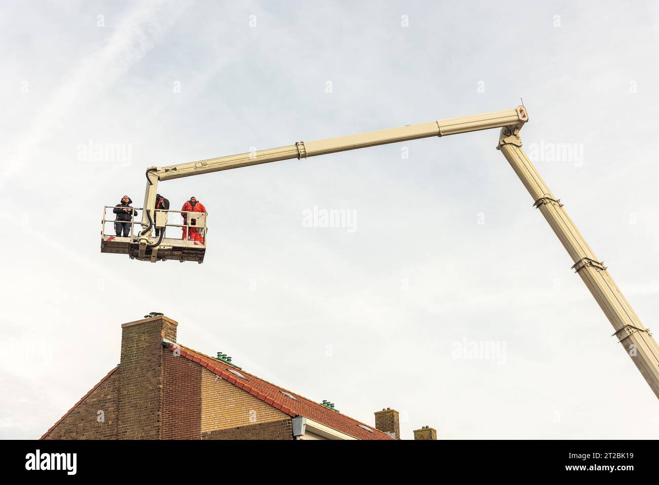 tre persone si trovano sulla piattaforma di una piattaforma aerea sopra un condominio Foto Stock