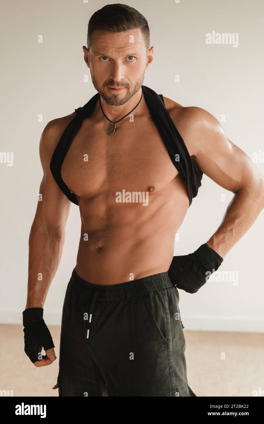 Un uomo muscoloso adulto con un torso nudo si trova in una stanza su uno sfondo chiaro. Foto Stock