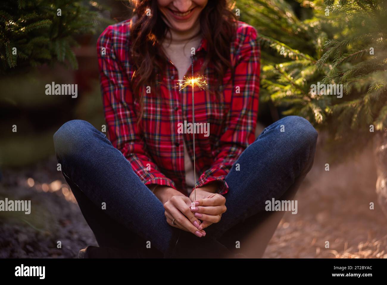 Brillante sparkler brucia nelle mani delle donne. La ragazza in camicia rossa a scacchi sorride. Atmosfera natalizia, Capodanno. Arredamento divertente per le vacanze. Foto Stock