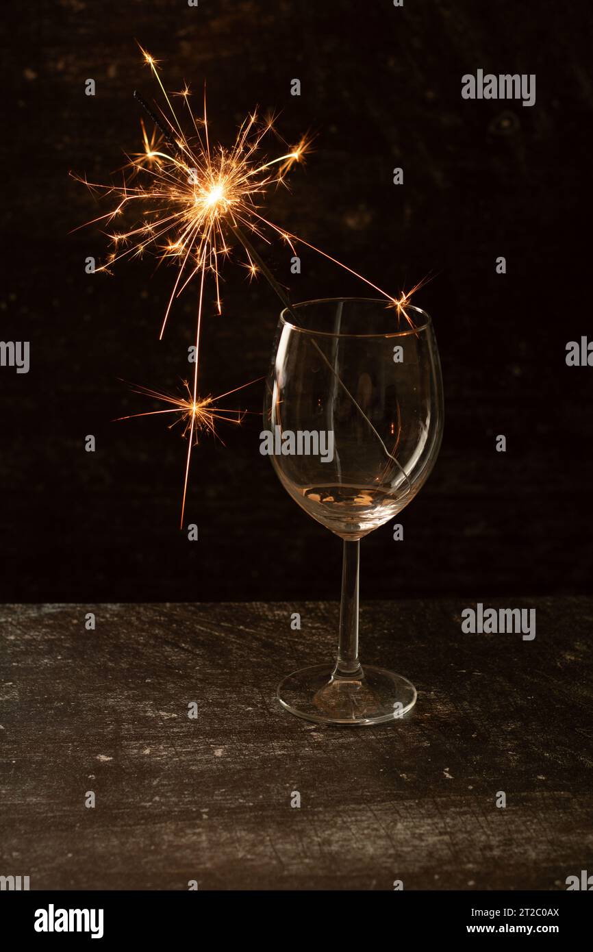 foto di un fuoco del bengala in un bicchiere di vino vuoto. nero, illuminato, apparecchiature di illuminazione, scintilla, colore, bengala, spazio copia Foto Stock
