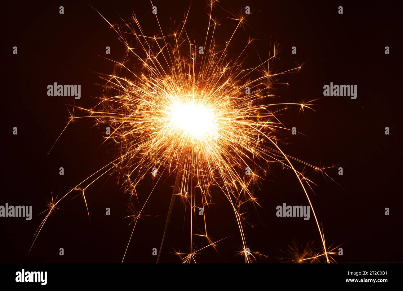 Foto a primo piano cattura la magia infuocata di uno sparkler alla festa di Capodanno. All'oscuro, brucia di brillantezza, creando un evento celebrativo Foto Stock