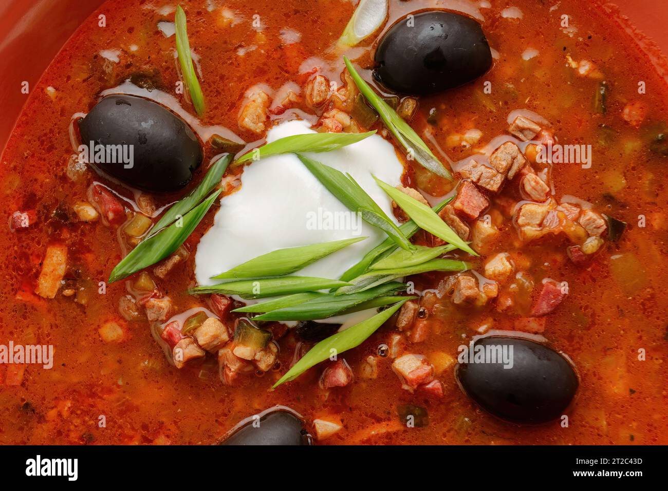 Zuppa Ucraina solyanka con carne, olive, panna acida, erbe aromatiche e limone Foto Stock