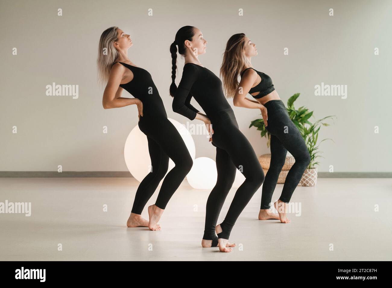 Un gruppo di ragazze di colore che fanno yoga posa in casa. Le donne sono impegnate nel fitness. Foto Stock