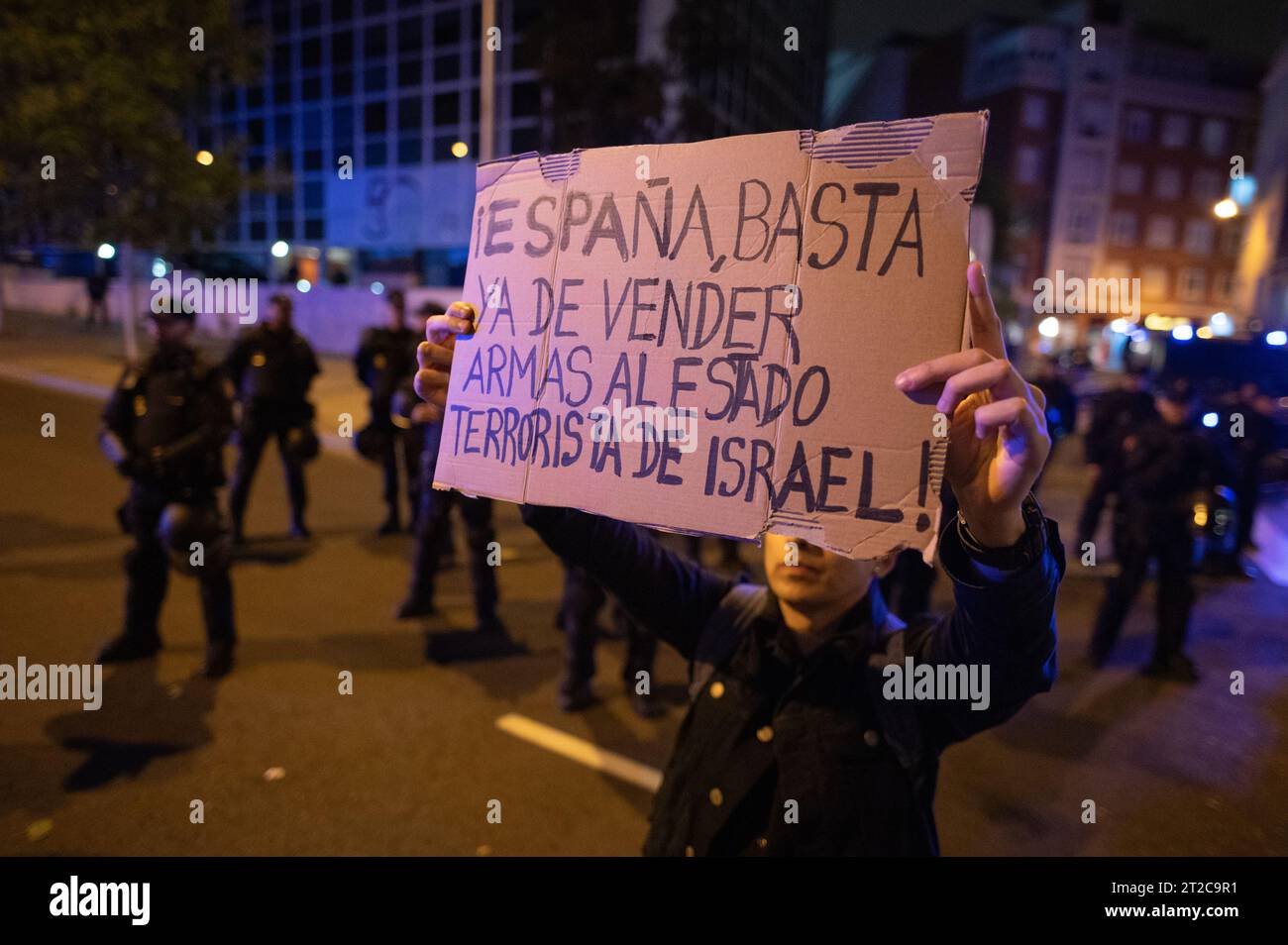 Gaza il 7 ottobre 2023, Un uomo si trova di fronte a un gruppo di polizia antisommossa che mostra un cartello con la scritta "Spagna, smettete di vendere armi allo Stato terroristico di Israele” durante una manifestazione a sostegno del popolo palestinese. La comunità palestinese di Madrid ha chiesto una protesta davanti all'Ambasciata di Israele dopo un'esplosione all'ospedale arabo di al-Ahli che ha ucciso centinaia di palestinesi. I manifestanti stanno manifestando contro gli attacchi israeliani alla Striscia di Gaza durante il conflitto israelo-palestinese dopo che il gruppo militante palestinese Hamas ha lanciato il più grande attacco a sorpresa da Gaza nell'ottobre scorso Foto Stock