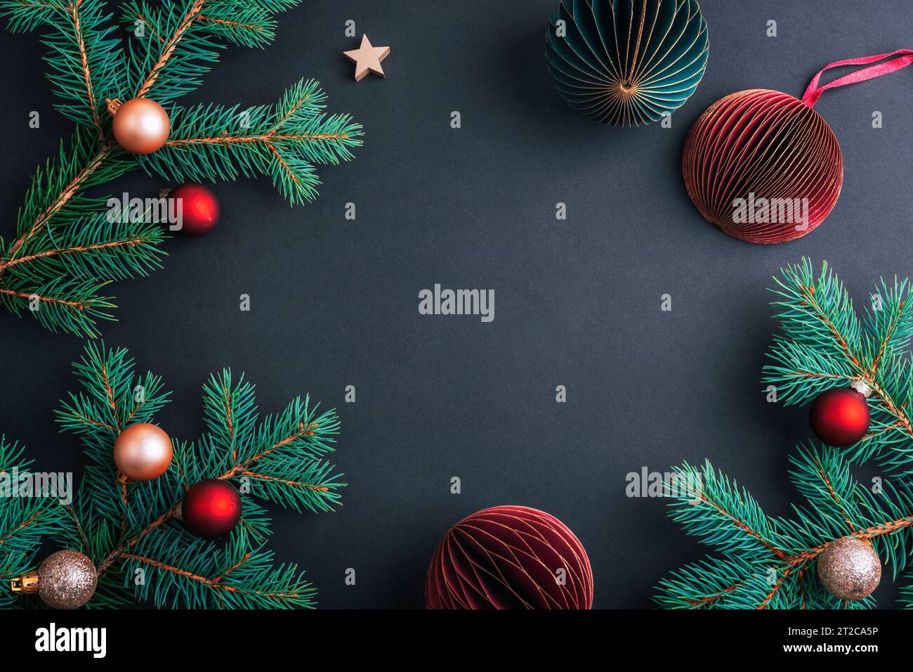 Cornice natalizia composta da rami di abete con palline natalizie su sfondo nero. Vista dall'alto, base piatta, spazio di copia. Foto Stock