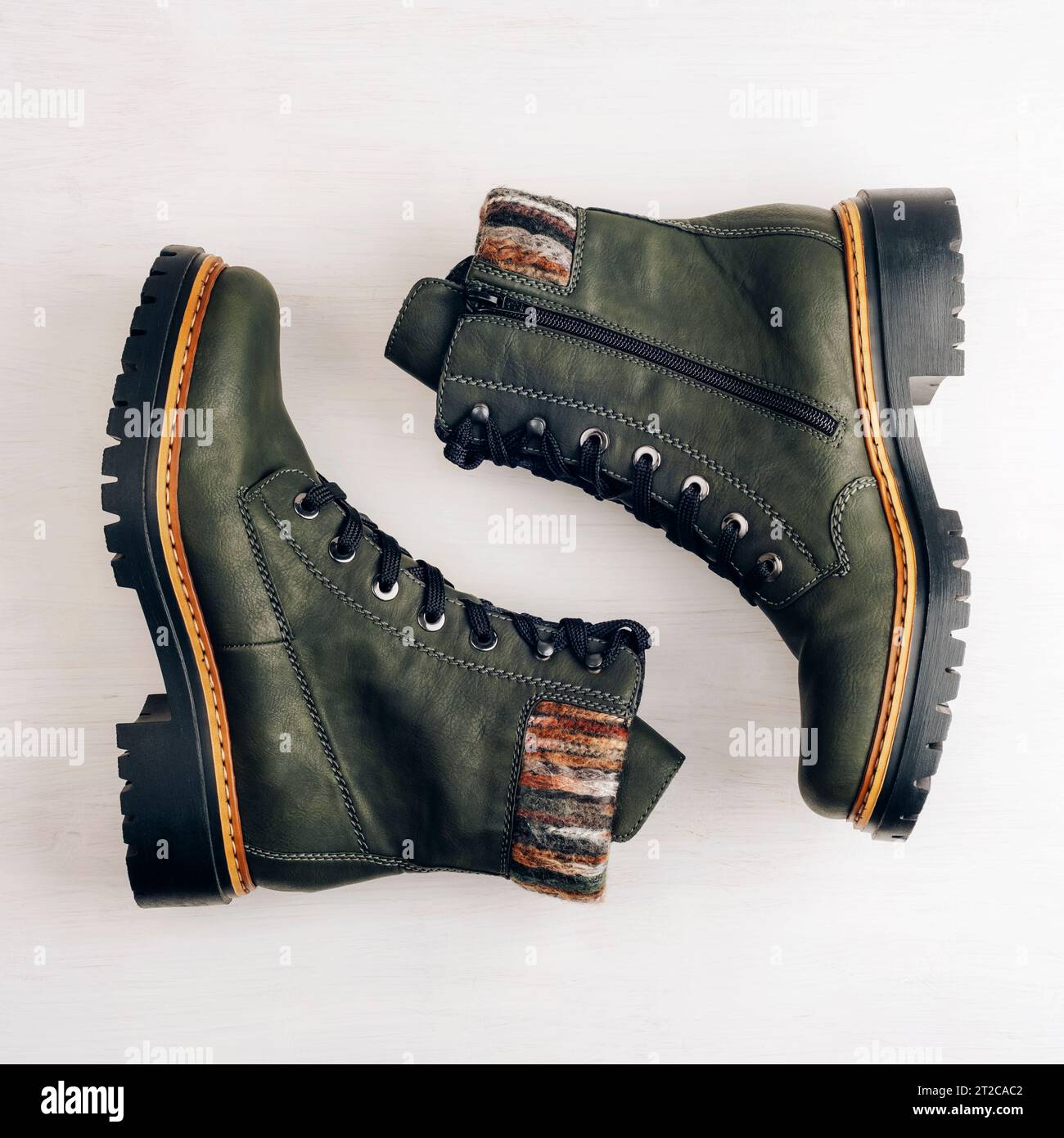 Stivali da donna verde scuro su sfondo bianco legno. Vista dall'alto, base piatta. Scarpe casual alla moda, negozio di vendita di scarpe autunnali o invernali. Foto Stock