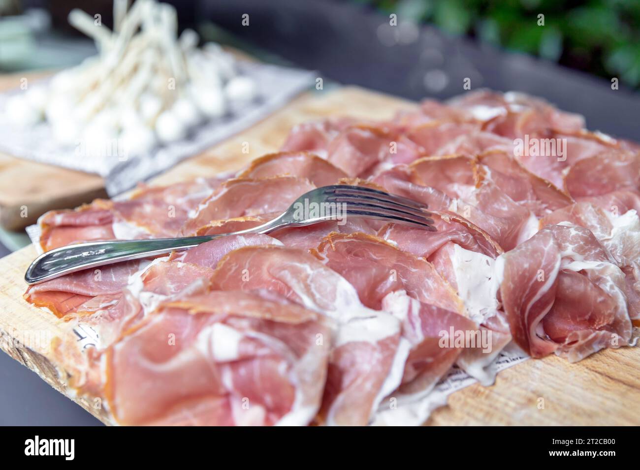 Fette sottili di prosciutto crudo su tagliere di legno, antipasti. feste. eventi. Foto Stock