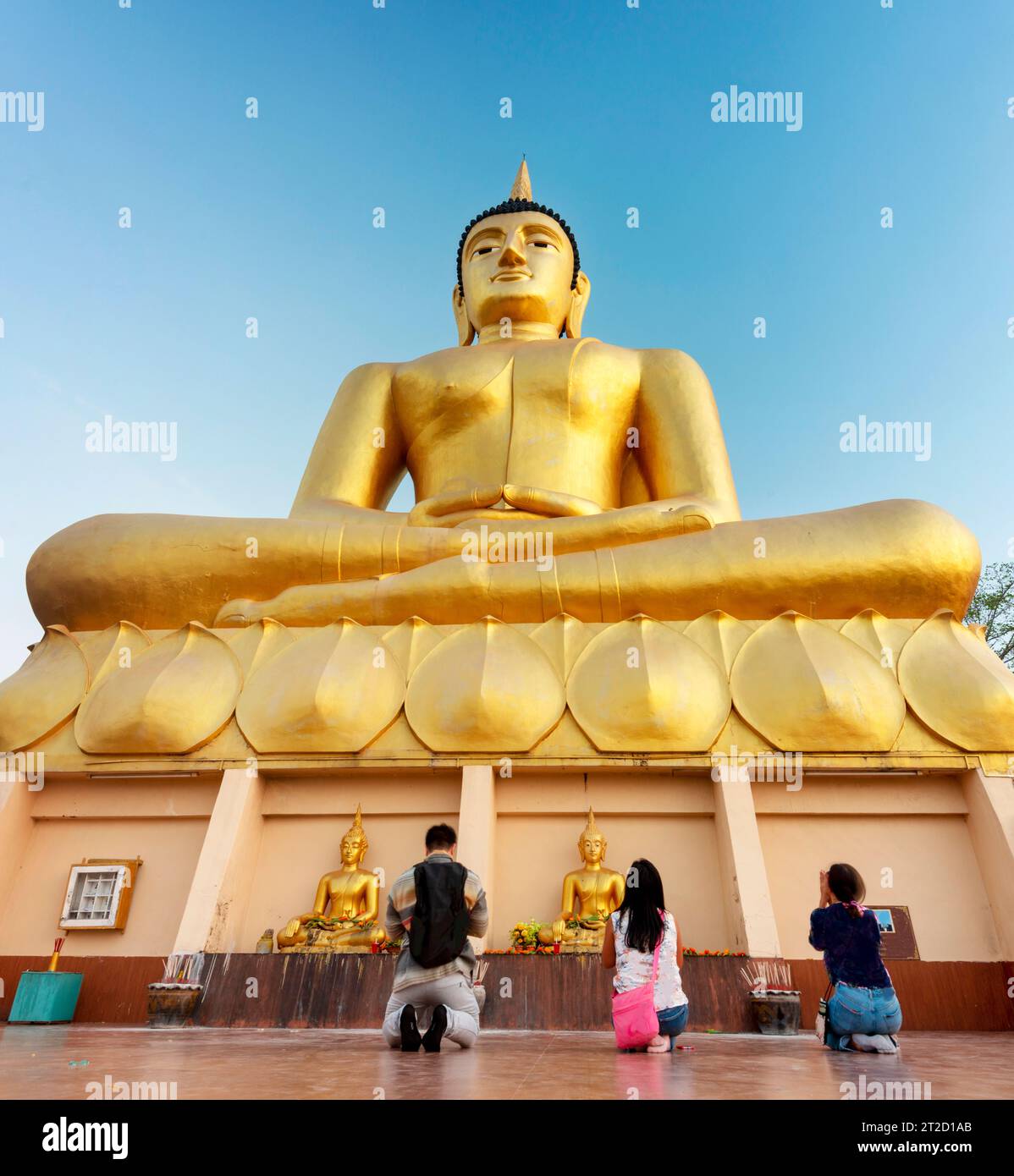 Adorando la bella e vibrante immagine dorata del Buddha, mentre il sole tramonta oltre, un popolare sito sacro e attrazione turistica che si affaccia su Pakse e sul Foto Stock