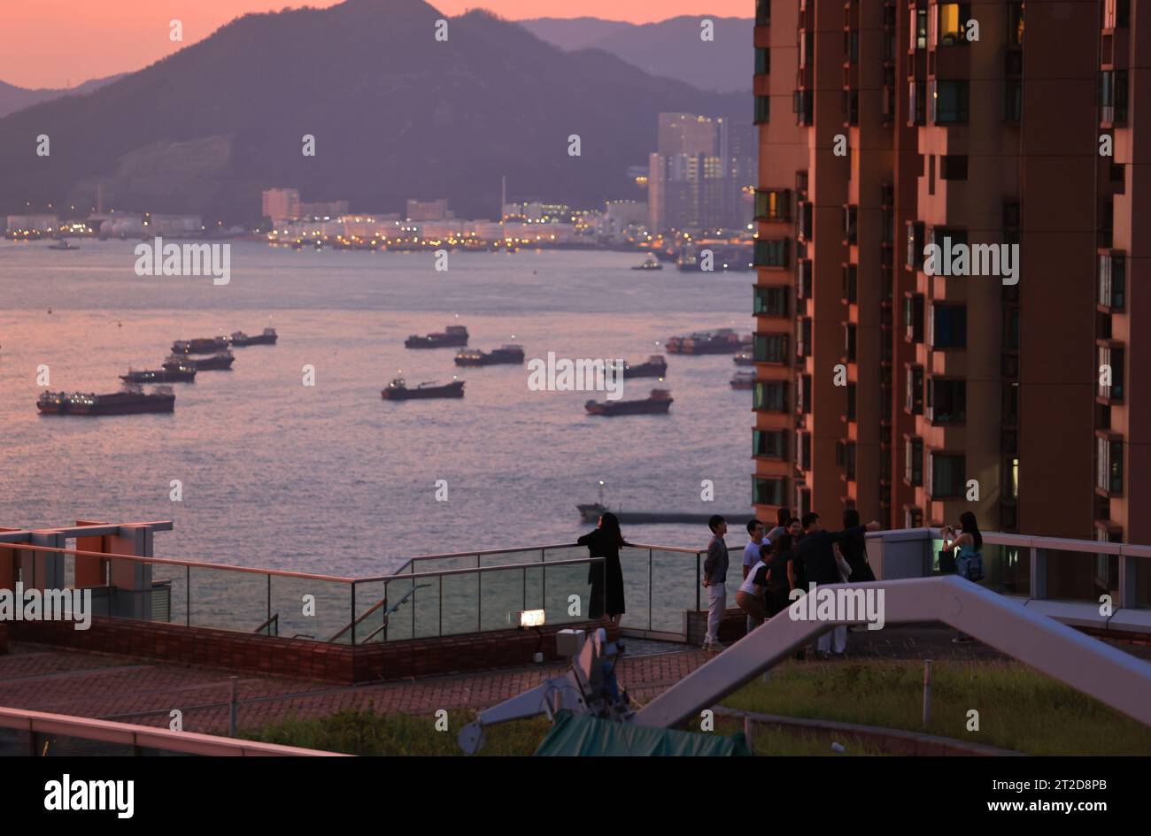 Paesaggio urbano di Hong Kong, il parco delle navi da carico sul mare, situato a Sheung Wan con parte del Victoria Harbour durante il tramonto e il bagliore Foto Stock