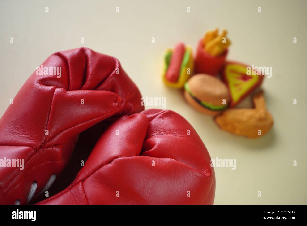 Immagine ravvicinata di guanto da boxe e cibi spazzatura come hamburger e patatine fritte. Combattere le cattive abitudini alimentari. Foto Stock