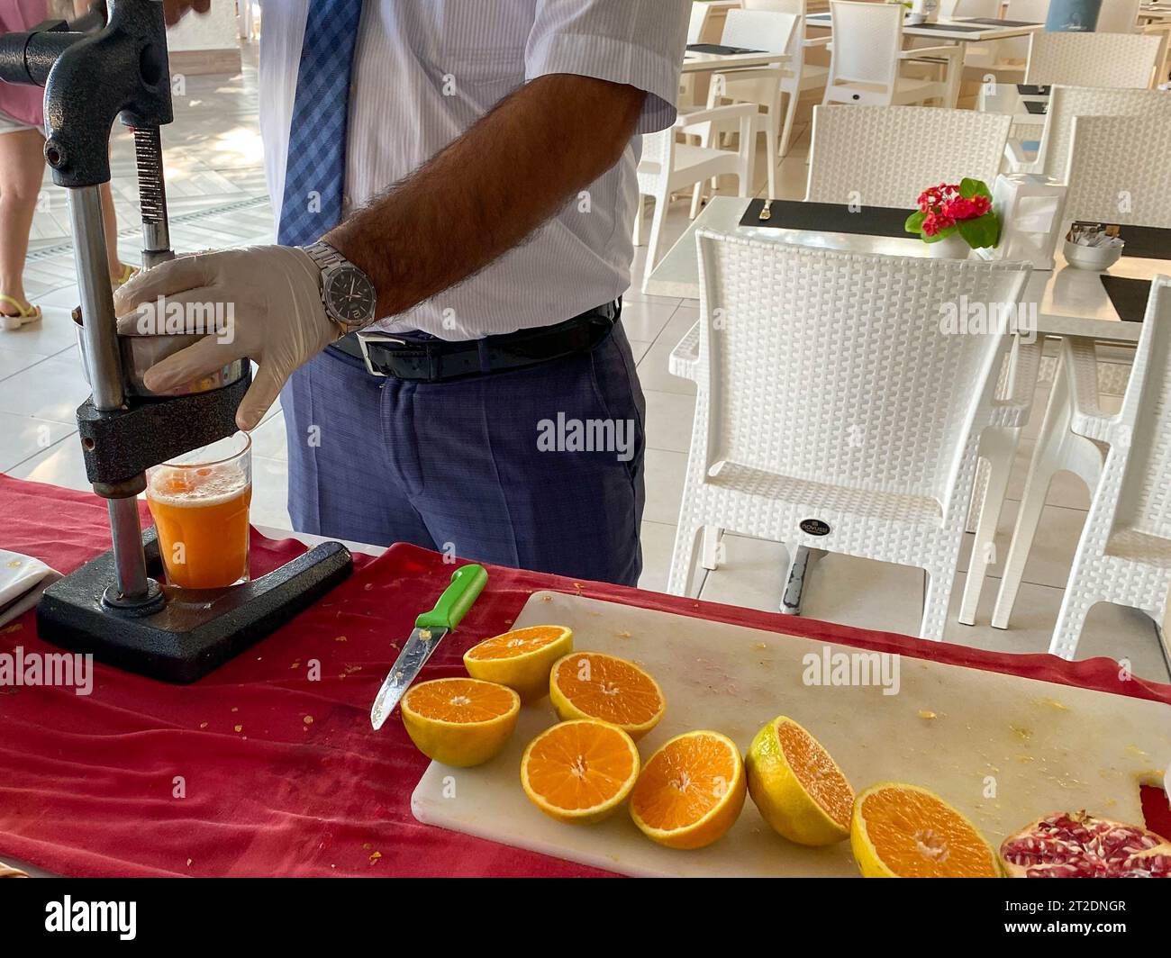 Un uomo prepara spremute d'arancia appena spremute con una centrifuga manuale in un hotel all-inclusive in un caldo resort turistico di campagna tropicale in vacanza Foto Stock