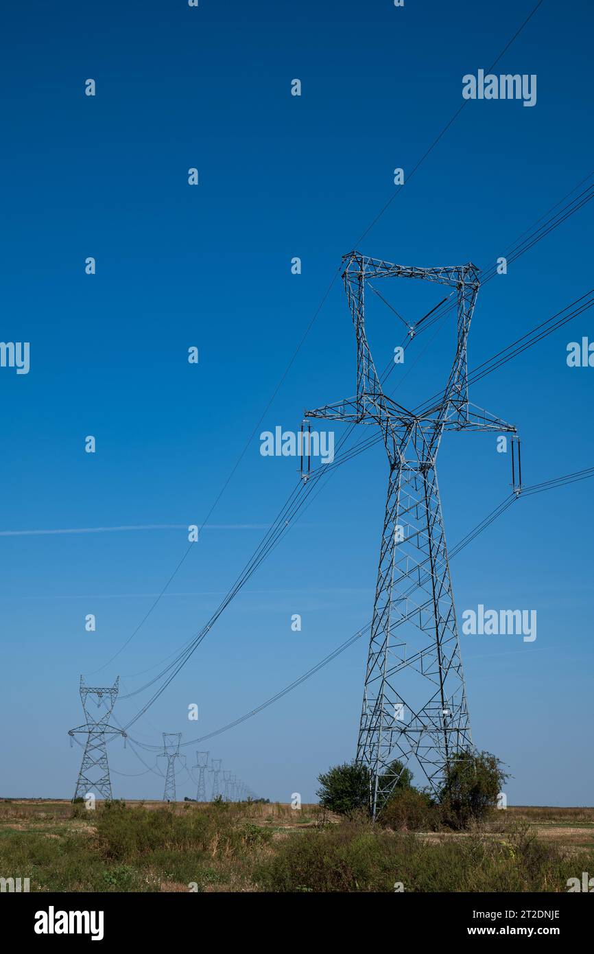 Torri o tralicci per la trasmissione di linee elettriche ad alta tensione in un campo in Europa. Niente persone. Foto Stock
