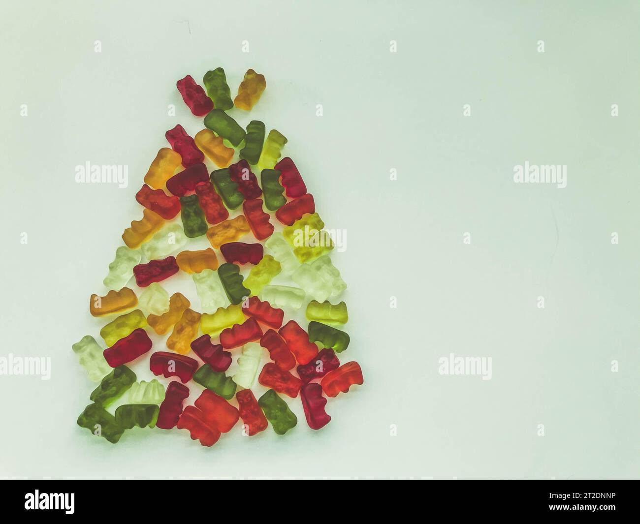 Albero di Natale fatto di gomme deliziose e dolci. marmellata sotto forma di orsi, bottiglie di limonata. Albero di Natale realizzato in colori vivaci e sw Foto Stock