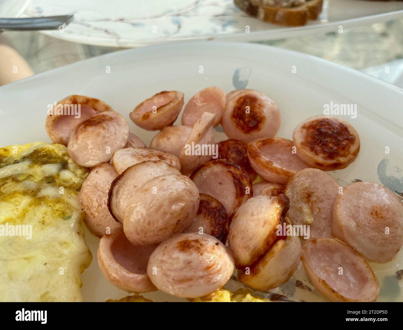 Abbondante e deliziosa colazione con salsicce fritte, salsicce a fette su un piatto con uova e omelette. Foto Stock