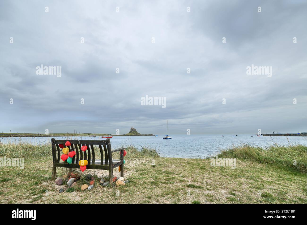 Cuori d'amore artigiani su una panchina sulla riva del mare al porto sulla Holy Island di Lindisfarne, Northumberland, Inghilterra. Foto Stock