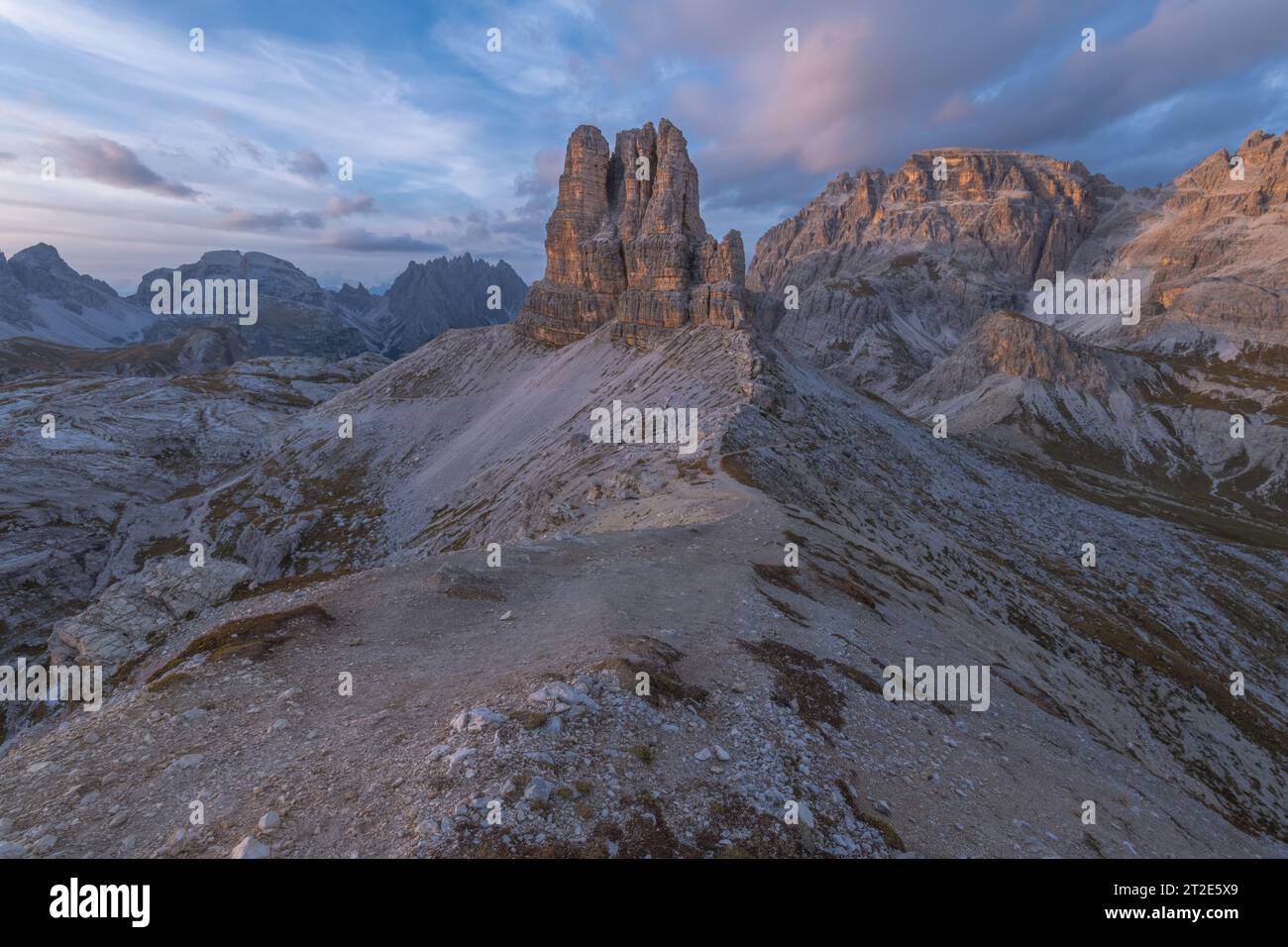 Tramonto con cielo dai colori pastello alla Toblin Tower nelle Dolomiti italiane. Monolite di roccia solitaria, butte indipendente circondato da imponenti cime montuose Foto Stock