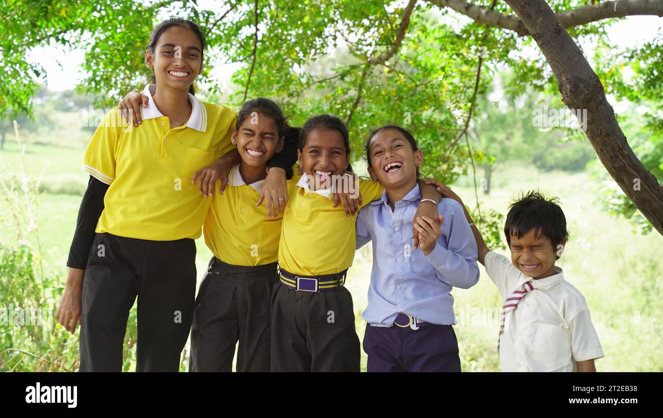 Un gruppo di ragazzi delle scuole rurali sorridenti in uniforme in piedi sul campo di risaie medio. Concetto di amicizia, educazione e solidarietà Foto Stock