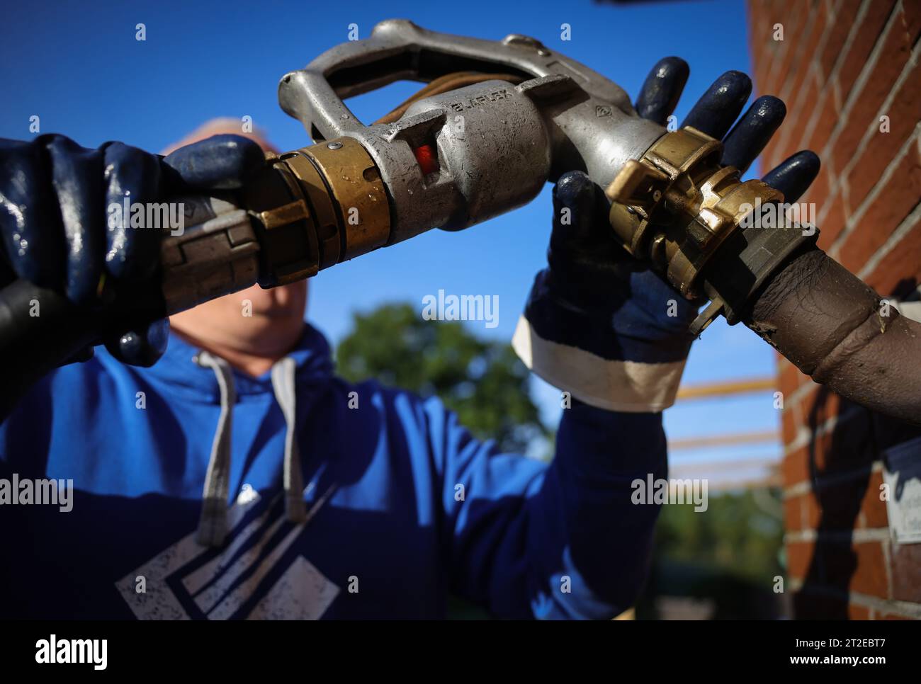 Bad Brahmstedt, Germania. 18 ottobre 2023. Un dipendente di un'azienda di gasolio e gasolio per riscaldamento collega un tubo flessibile con ugello a un bocchettone di riempimento per la consegna dell'olio per riscaldamento a un cliente in una casa a conduzione familiare. Credito: Christian Charisius/dpa/Alamy Live News Foto Stock