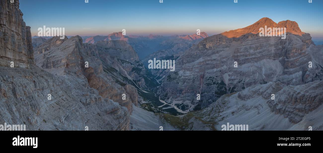 Splendido tramonto alpino sulle montagne delle Tofane vicino a Cortina, il cuore delle Dolomiti italiane. Cime dorate delle montagne e profonda valle glaciale Foto Stock