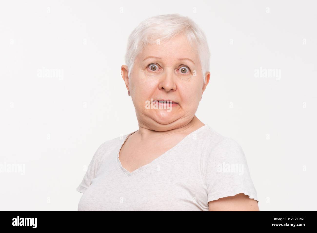 Anziano donna caucasica che esprime scioccata e sensazione di paura in studio girato su sfondo bianco isolato Foto Stock