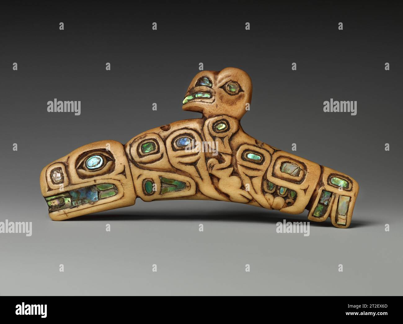 Amuleto Tlingit, nativo americano CA. 1840–70 i popoli del Nord-ovest Pacifico condividono una visione del mondo sciamanica. Gli sciamani impiegano tecniche come il digiuno e la danza per entrare in stati di coscienza alterati, in cui hanno visioni che li guidano nella guarigione o nella consulenza alla comunità. Indossano ciondoli protettivi o spiritualmente carichi, come questo esempio, e a volte li danno ai pazienti come farmaci potenti. Qui, vediamo due forme animali che potrebbero essere state emblemi ancestrali di un particolare sciamano: Una graziosa balena subacquea e un raptor con ali allungate. Il natu che cambia colore Foto Stock