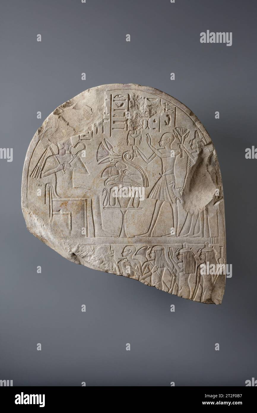 Parte superiore di una Stela New Kingdom ca. 1390–1352 a.C. questa stele raffigura il dio Osiride, a sinistra, che riceve offerte da un uomo che tiene un braciere nella mano destra, seguito da sua moglie, Henutnefret, che tiene un mazzo di gigli d'acqua. Il titolo dell'uomo, sdm ?Š (servo) è conservato nella colonna centrale del testo, ma il suo nome, nella colonna successiva a destra, è stato violato. Il geroglifico iniziale, una foglia di canna, è ancora visibile, quindi probabilmente era Amenofi (Amon è soddisfatto), o Amenemhat (Amon è il più importante). Entrambi i nomi, che includono riferimenti al dio Amon, sono stati attaccati du Foto Stock