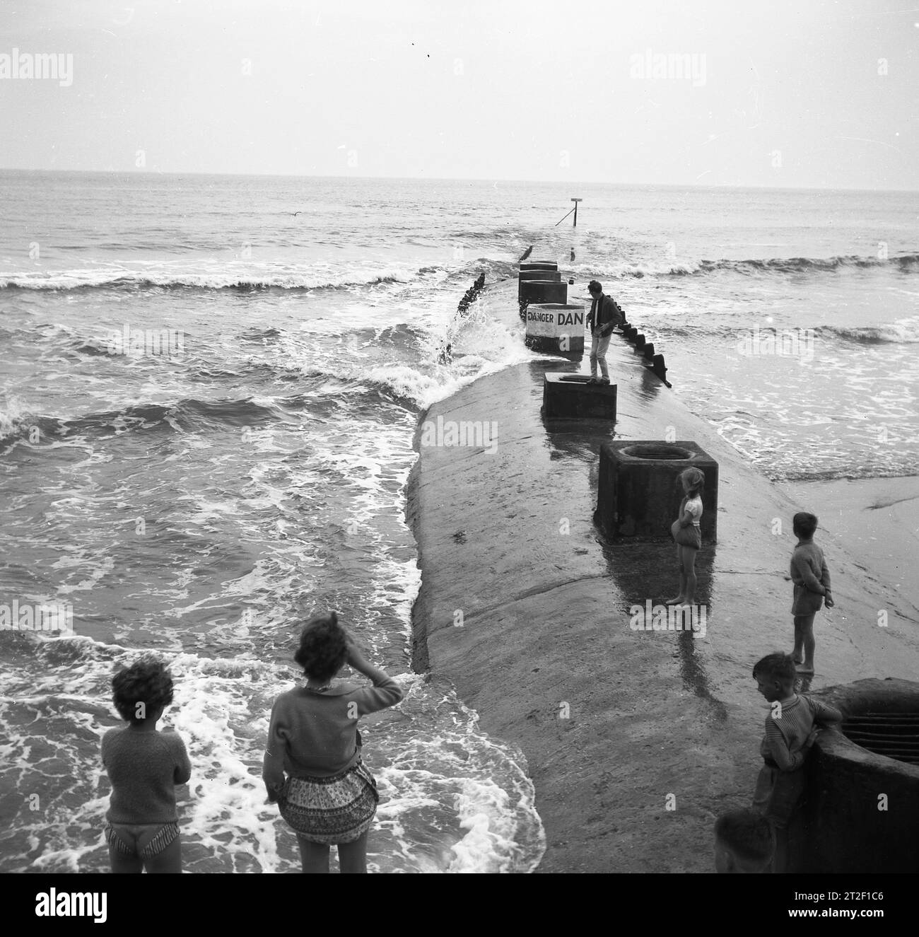 1950, storica, difesa costiera, persone su una grande frangiflutti di cemento o groyne sulla costa di Bridlington, East Yorkshire, Inghilterra, Regno Unito...... sembra un sottomarino che emerge dalle profondità! Foto Stock
