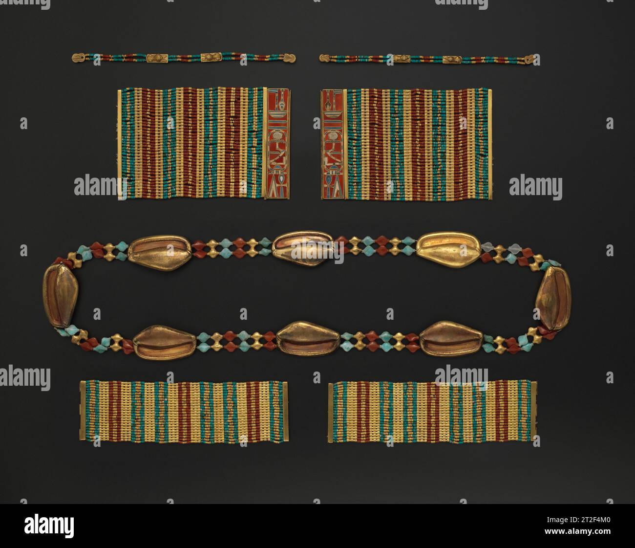 Cowrie Shell Girdle, Lion Bracelets, Bracelets with the Name of Amenemhat III, and Anklets of Princess Sithathoryunet Middle Kingdom CA. 1887–1813 a.C. insieme al pettorale, questi braccialetti, caviglie e cintura sembrano appartenere a una serie di gioielli formali che potrebbero essere stati indossati durante un rito speciale. Sebbene gli oggetti condividano uno schema di colori, le variazioni nella produzione suggeriscono che si sono accumulati nel tempo. Tutti i pezzi sono stati ricostruiti da elementi sciolti trovati sparsi intorno alle scatole decadute di Sithathoryunet. I braccialetti sono intarsiati con il nome di re Amenemhat III La circonferenza Foto Stock