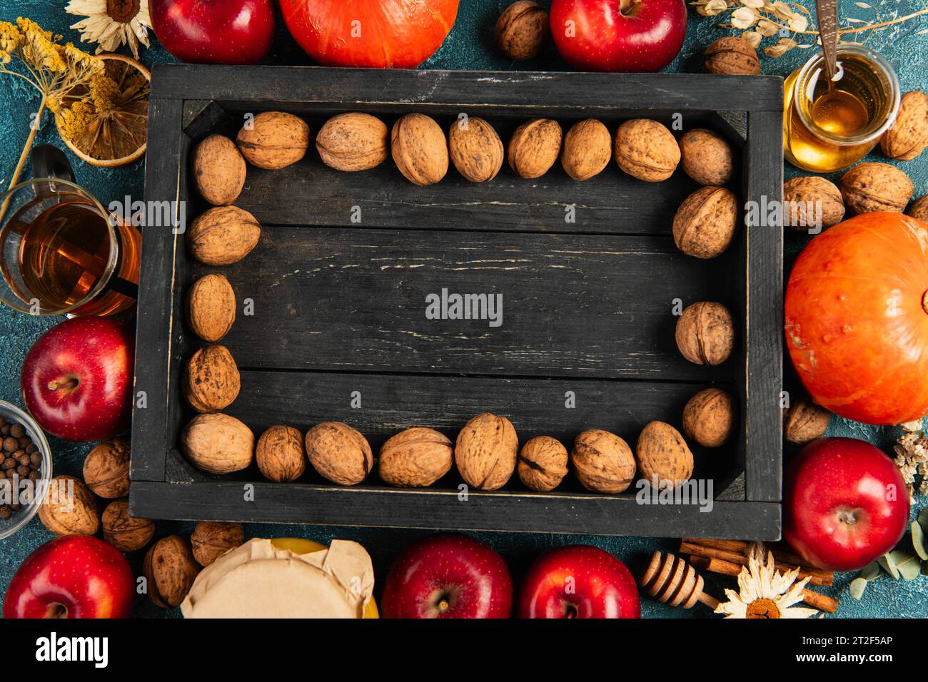 sfondo colorato per il giorno del ringraziamento con noci su vassoio di legno nero circondato da oggetti per il raccolto autunnale Foto Stock