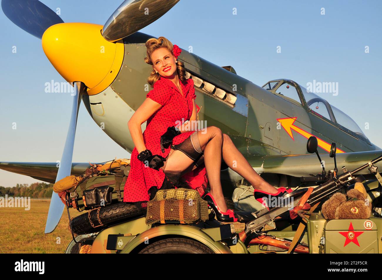 Sexy abito rosso bellezza in posa con una moto russa e un aereo militare russo Yak-9. Foto Stock