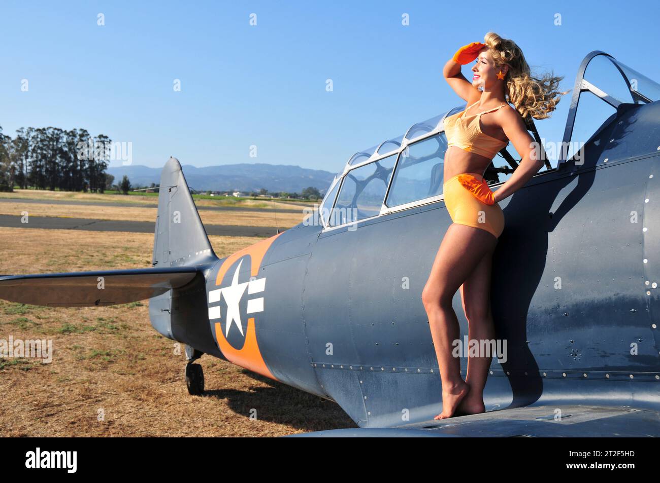 Adorabile donna in lingerie vintage arancione e aeroplano SNJ abbinato ai colori. Foto Stock