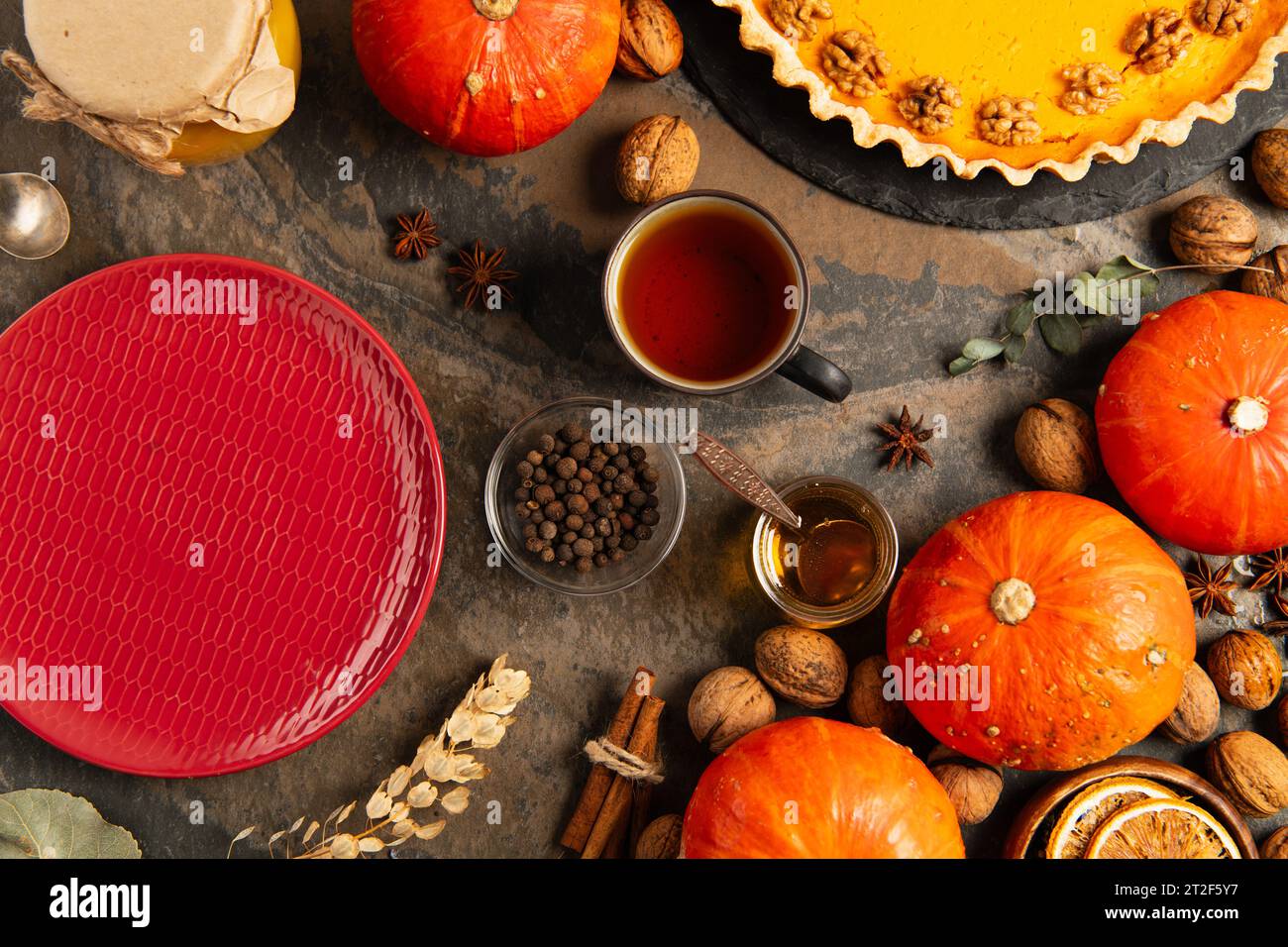 coloratissimi oggetti autunnali del giorno del ringraziamento, piatto in ceramica rossa vicino alle zucche arancioni e torta di zucca Foto Stock