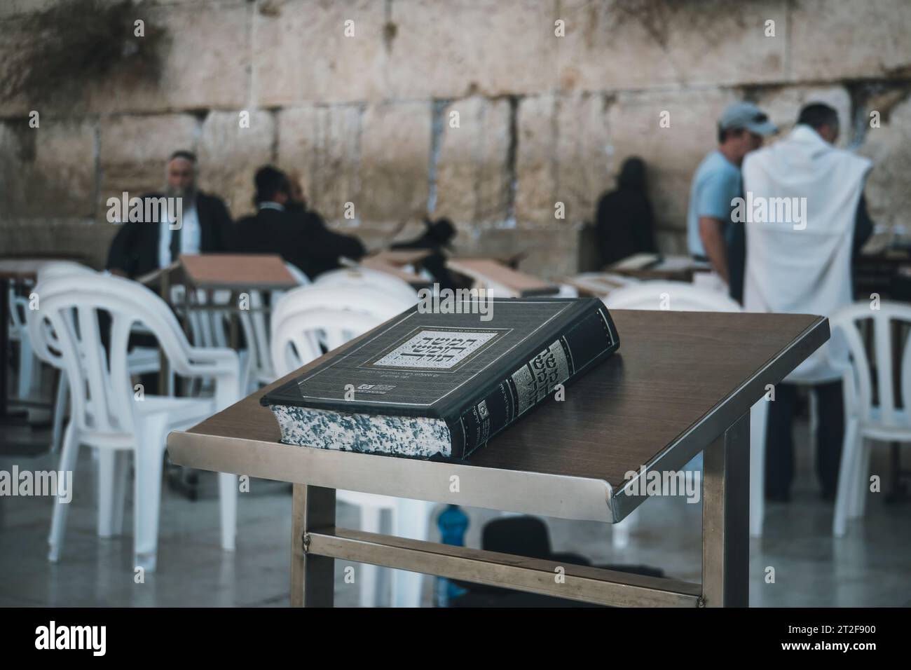 Primo piano del libro sacro ebraico chiuso Torah, lasciato sul tavolo con gli ebrei ultra-ortodossi al muro del pianto sullo sfondo. Libro con writ ebraico Foto Stock