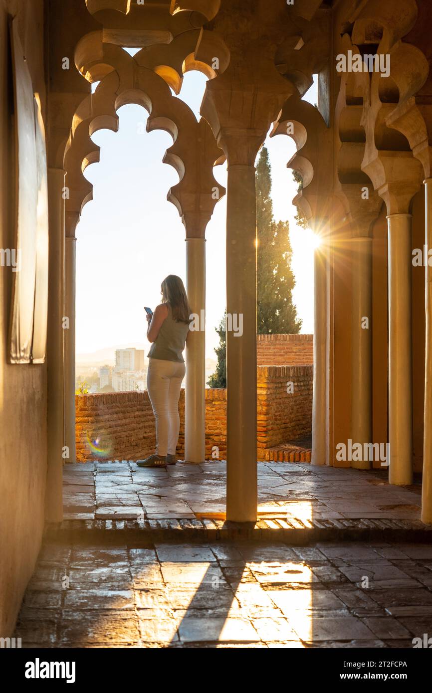 Un turista ha inseguito una colonna al tramonto dalle porte arabe di un cortile dell'Alcazaba nella città di Malaga, Andalusia. Spagna. Medievale Foto Stock