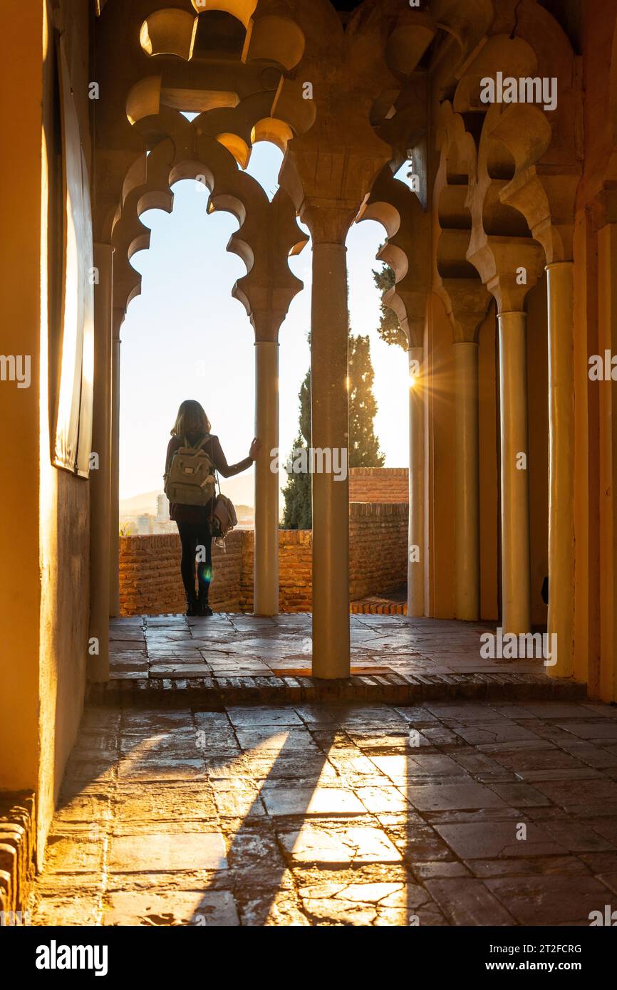 Una giovane donna al tramonto dalle porte arabe di un cortile dell'Alcazaba nella città di Malaga, Andalusia. Spagna. Fortezza medievale in arabo Foto Stock