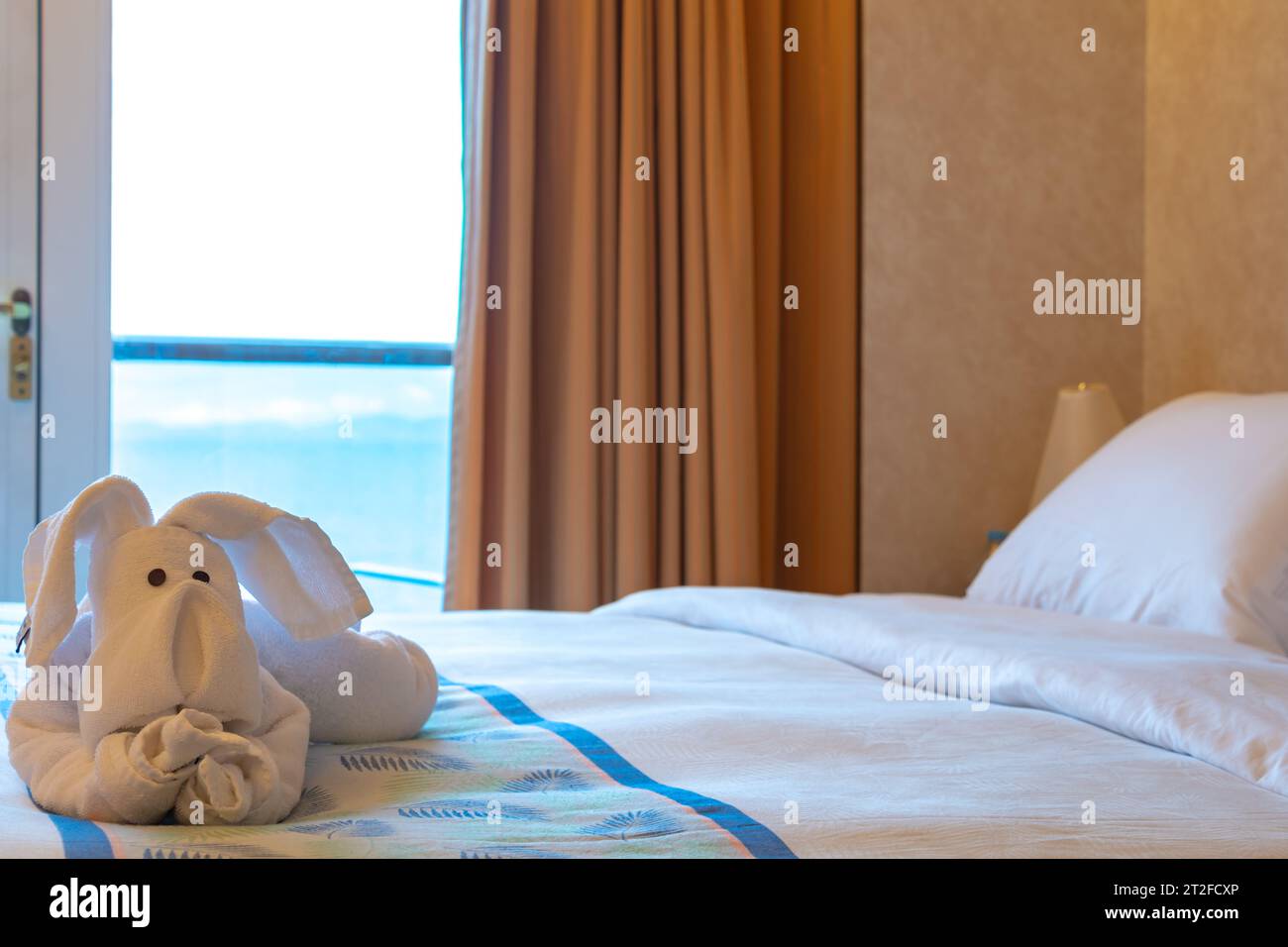 Camera d'hotel con balcone e vista mare. Camera accogliente e sul letto c'è un asciugamano a forma di elefante Foto Stock