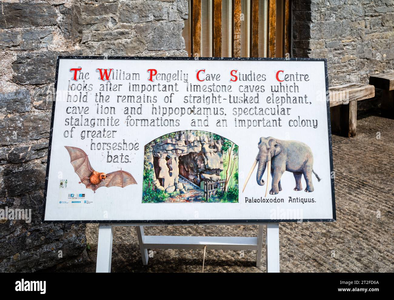 Un segno bianco con immagini di un mamouth e di un pipipistrello che descrive il ruolo del William Pengelly Cave Studies Centre nella protezione e nello studio dell'antico li Foto Stock